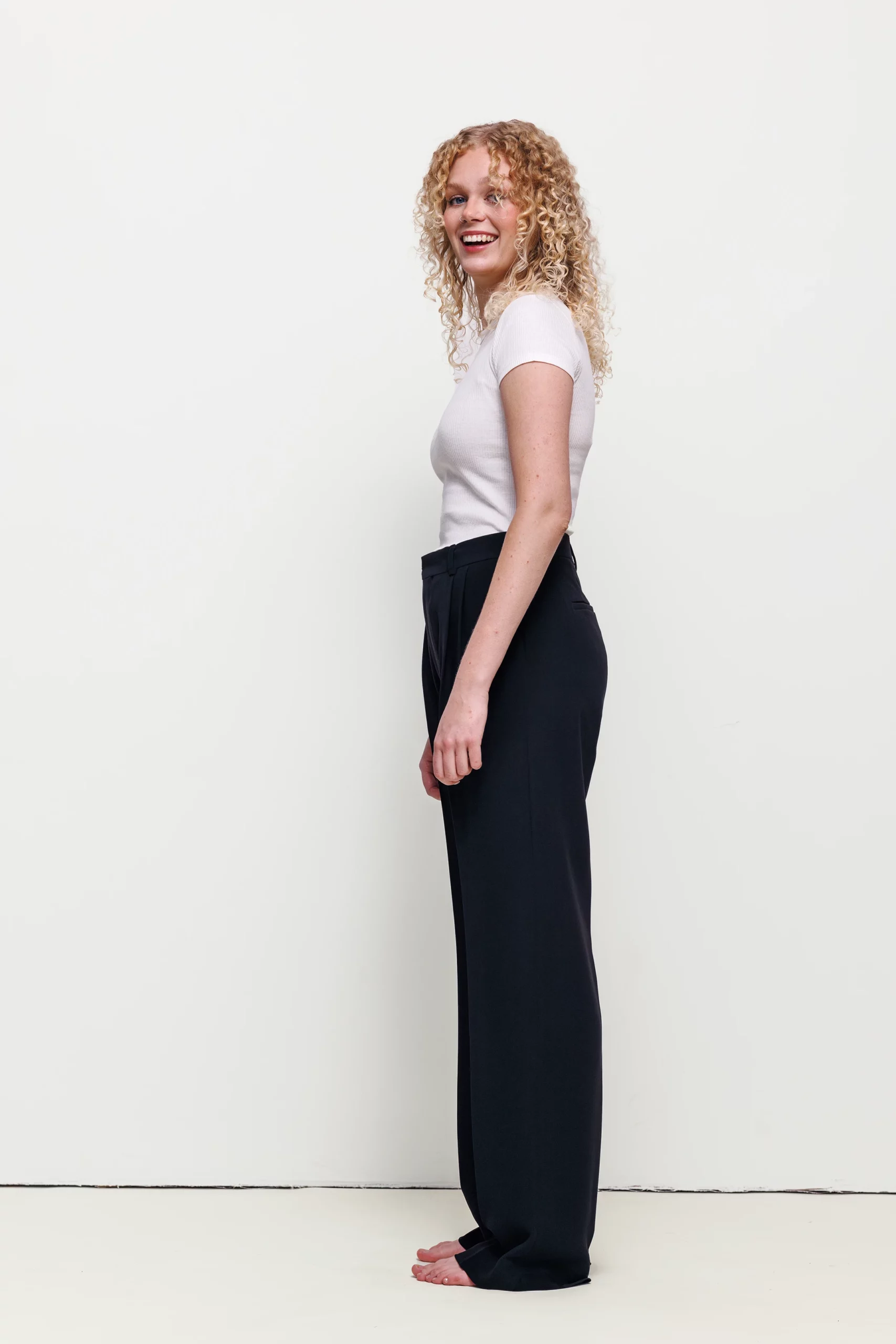 a woman with curly blonde hair and black pants
