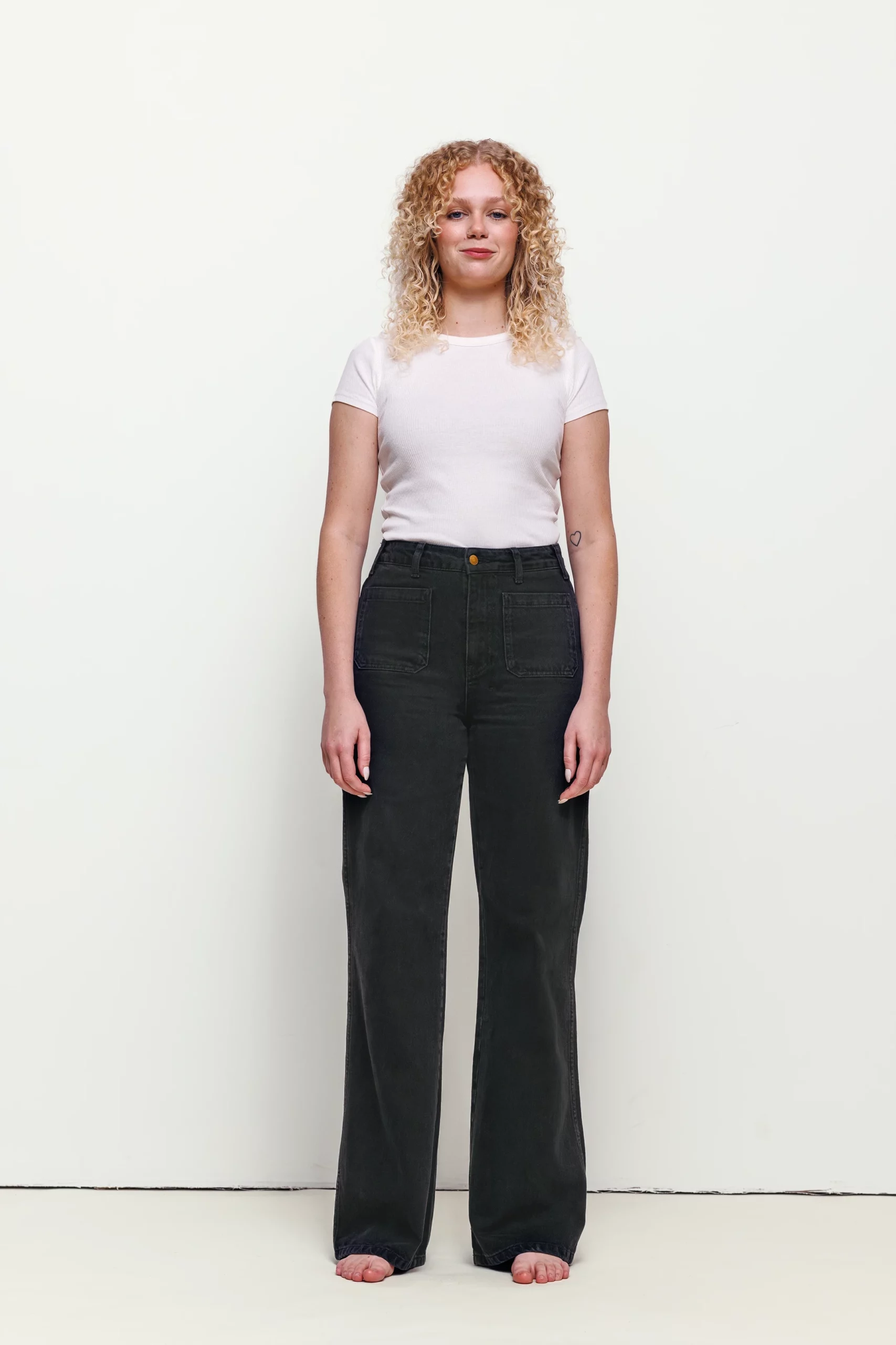 a woman with blonde curly hair wearing black pants and white shirt