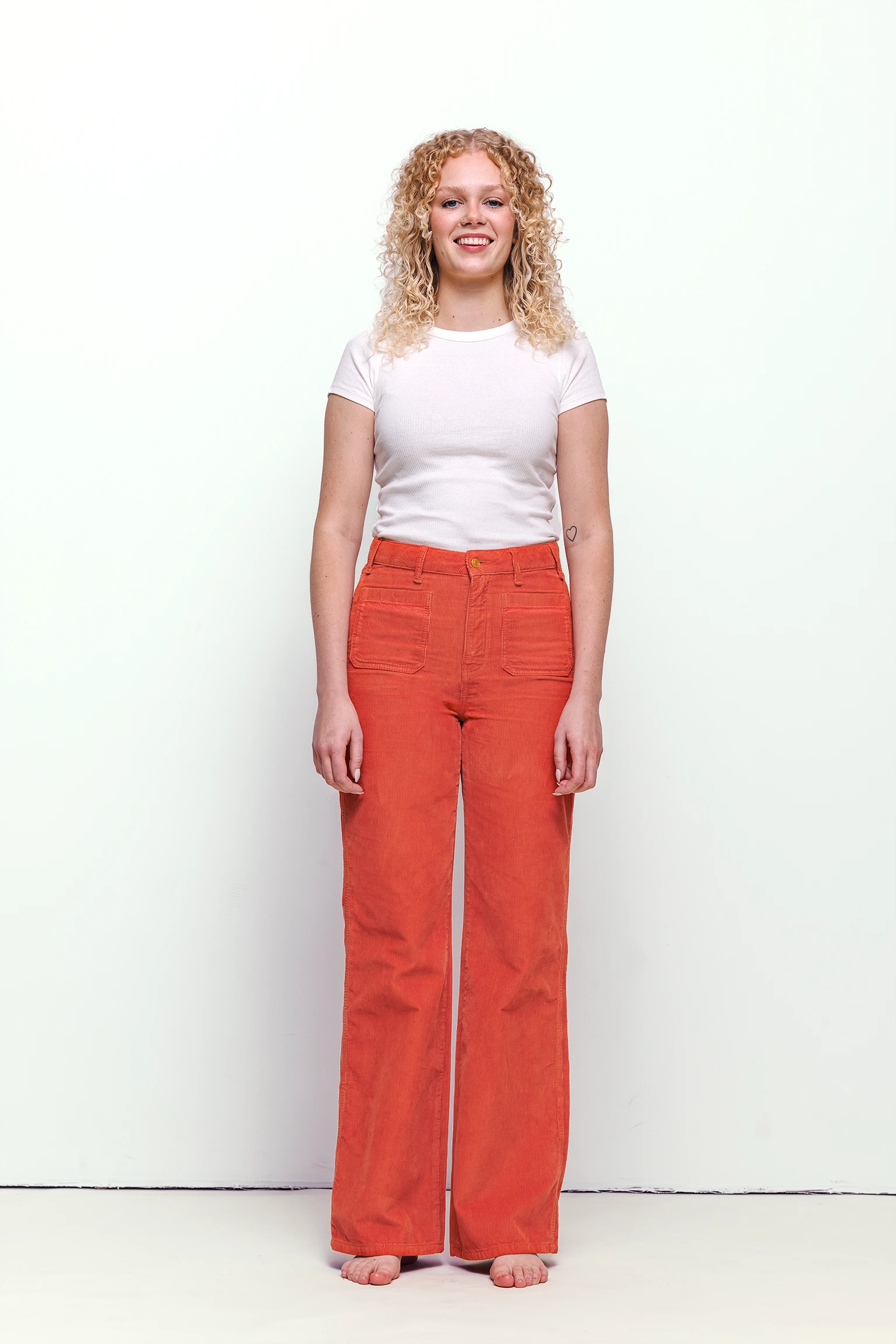 a woman with curly blonde hair wearing red pants and white shirt