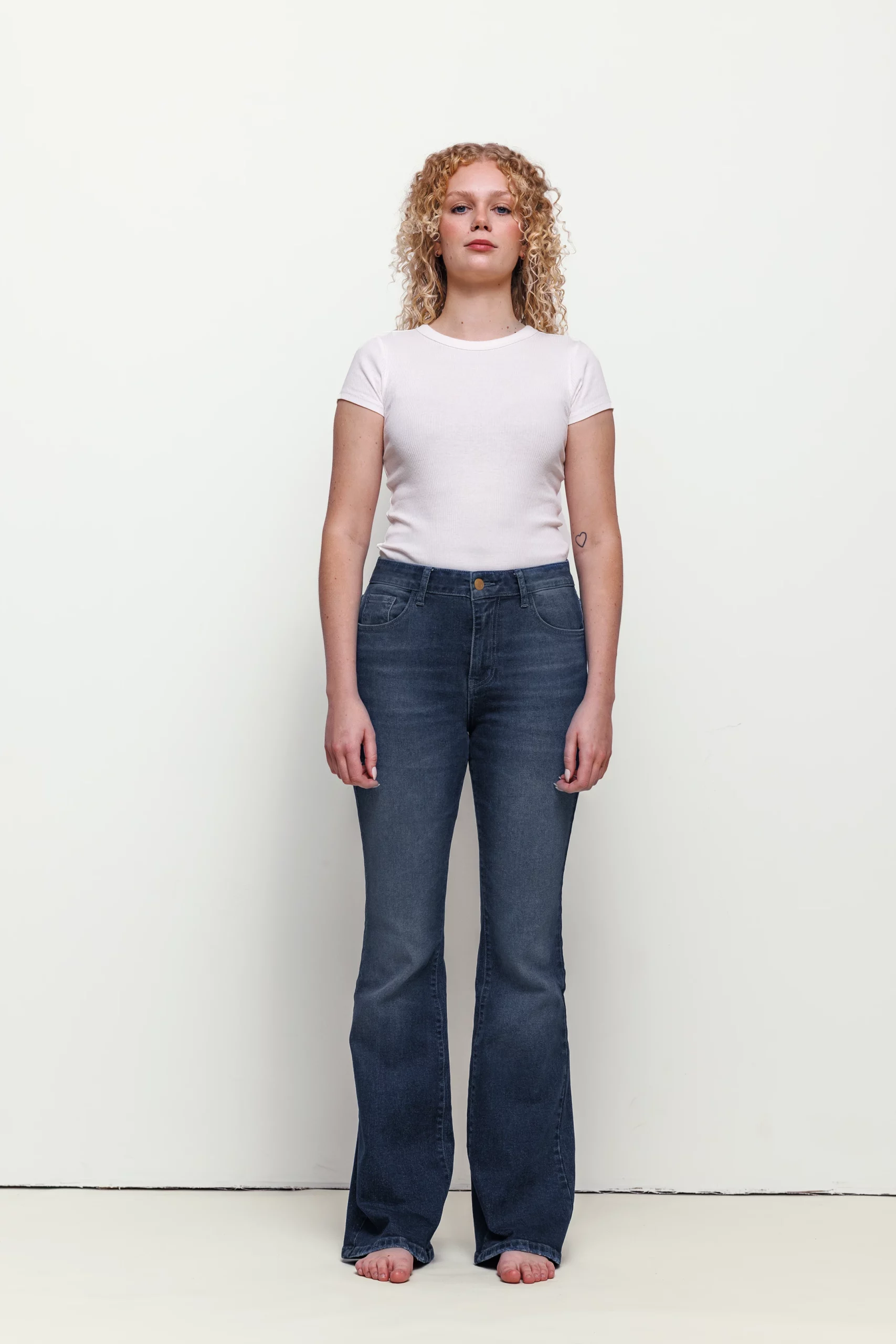 a woman with curly blonde hair wearing jeans and a white shirt