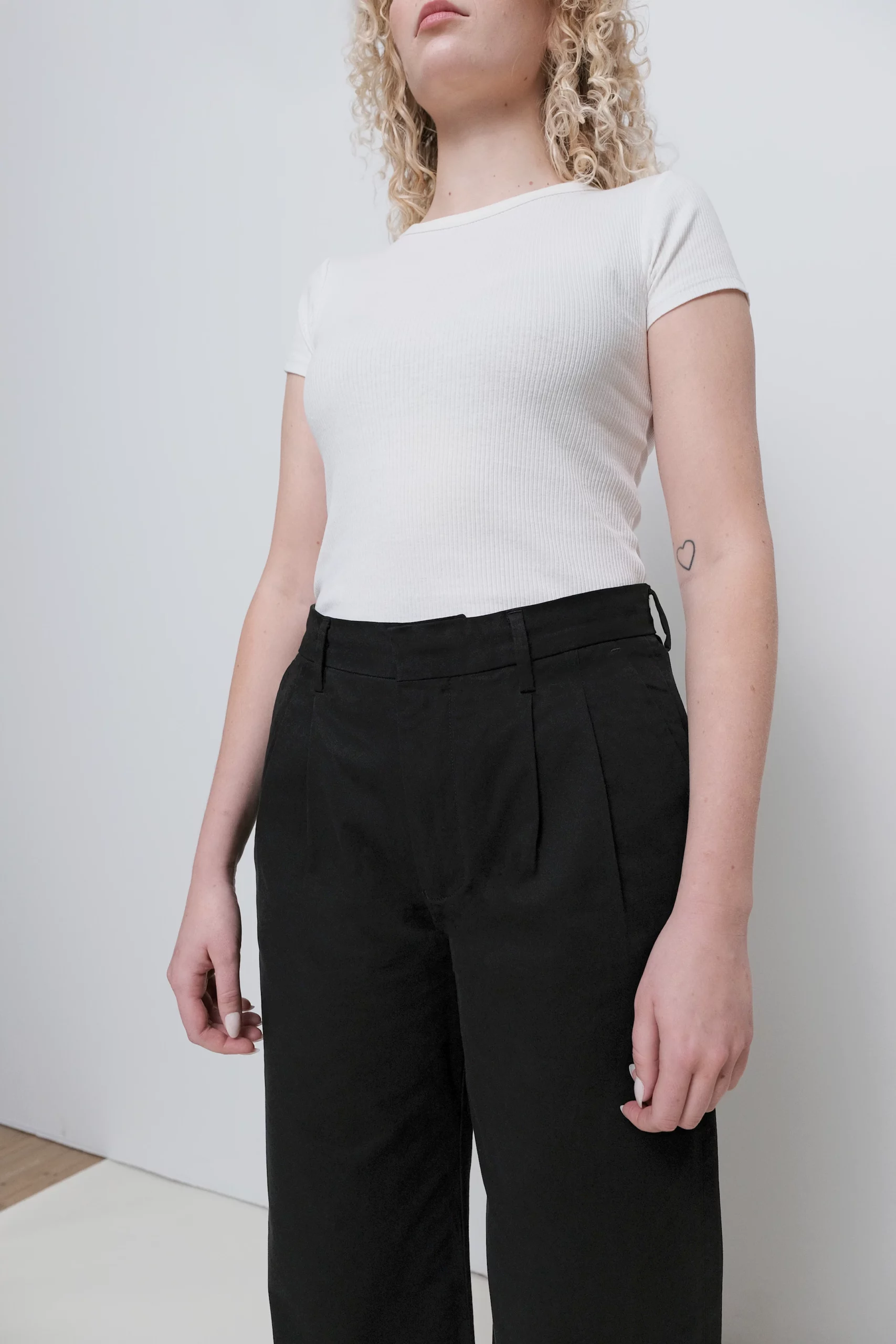 Närbild framifrån med modell som har på sig svarta chinos.